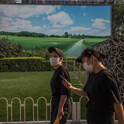 Women walk past a banner showing a green field and blue sky in the shopping and residential area of Sanlitun, in Beijing, on September 3. Beijing’s clampdown on the residential property market is much tougher than anything implemented, or contemplated, in other major economies. Photo: EPA-EFE