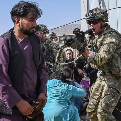 A US soldier points his gun at an Afghan man at Kabul airport on August 16 as thousands of people tried to flee Taliban rule. Photo: AFP