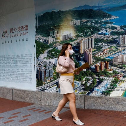 A woman walks past a property advertisement for Emerald Bay by China Evergrande in Hong Kong, on August 25. Evergrande’s liquidity crisis is not an isolated case, and debt default risks remain a blight of our times. Photo: Reuters