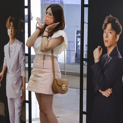 A woman poses with large portraits of members of the boy group Mirror, at an exhibition in Harbour City in Tsim Sha Tsui on September 11. Photo: Dickson Lee