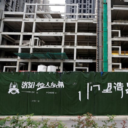 A peeling logo of the Evergrande Oasis, a housing complex developed by Evergrande Group, is seen outside the construction site where the residential buildings stand unfinished in Luoyang, Henan province, on September 16. Photo: Reuters