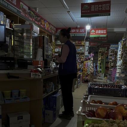 A woman buys groceries at a mini market using a gasoline generator to power a light bulb during a blackout in Shenyang, in Liaoning province, on September 29. Power cuts have disrupted manufacturing and daily life in China. Photo: AP 