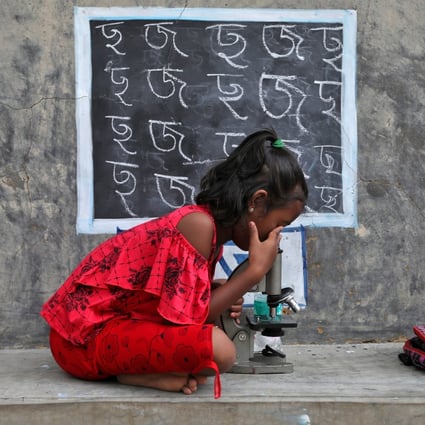 A girl with no access to internet facilities and gadgets uses a microscope as she attends an open-air class outside a house with its walls converted into blackboards as schools remained closed at a village in the Indian state of West Bengal on September 13. Photo: Reuters