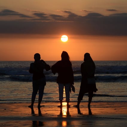 People watch the sunset at Kuta beach near Denpasar in Bali on October 7. The island’s international airport is set to reopen on October 14. Photo: AFP