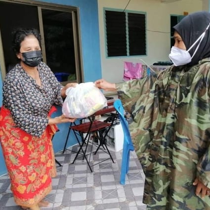 A woman in Phuket, Thailand, receives a Life Bag containing enough basic food items to feed a family of four for four days, distributed by One Phuket, an alliance of small tourism businesses. 