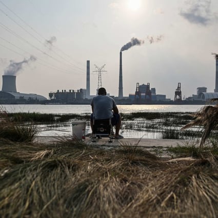 A fisherman sits by the Huangpu river across from the Wujing Coal-Electricity Power Station in Shanghai on September 28. Photo: AFP