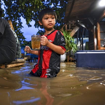 A child holds a drink at a flooded Chaopraya Antique Cafe in Nonthaburi, north of Bangkok, on October 7. Photo: AFP