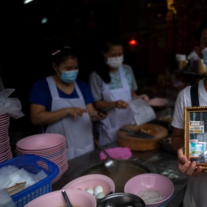 Adulwitch Tangsupmanee, 42, holds up a picture of his father Chanchai Tangsupmanee, who died of Covid-19 in July, at his late father’s food stall in Bangkok’s Chinatown. He didn’t hesitate to step into his father’s shoes, but heirs to other street-food stalls in the Thai capital did think twice before taking the plunge. Photo: Reuters