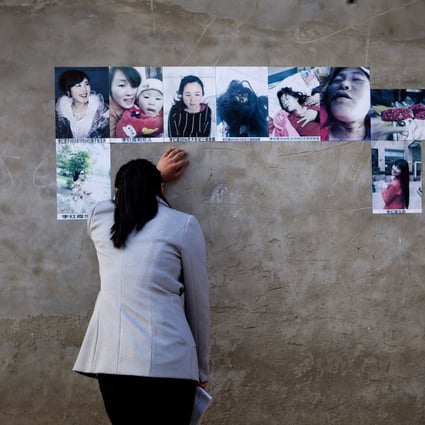 A woman cries looking at the pictures of her dead sister pasted on the wall of her former home in Zhang village, Henan Province, central China. Photo: Getty 