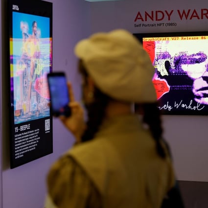 A visitor takes a photo in front of digital work ‘Untitled (Self-Portrait)‘ by Andy Warhol and digital artist Mike Winkelmann, known as Beeple, at the Digital Art Fair, in Hong Kong, September 30, 2021. Photo: Reuters