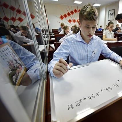 Participants write Chinese characters on white boards at the final of a Chinese language dictation contest at a Vladivostok Confucious Institute in Russia. Photo: Getty Images