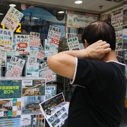 A potential customer looks at ads in the window of a property agency office in North Point, Hong Kong. Photo: Nora Tam