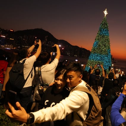 Hong Kong residents take photos of Christmas decorations at the waterfront promenade in West Kowloon Cultural District. The Hospital Authority has advised people to get vaccinated against the seasonal flu as the weather turns cooler. Photo:  Nora Tam