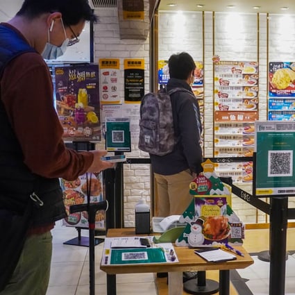 People use the ‘Leave Home Safe’ contact-tracing app to enter a restaurant in Admiralty. Hong Kong authorities are considering a proposal to introduce vaccine passports and ban unvaccinated people from venues such as restaurants. Photo: Sam Tsang