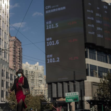 A woman walks on the street next to a large screen showing the Shanghai stock exchange data. Photo: EPA-EFE