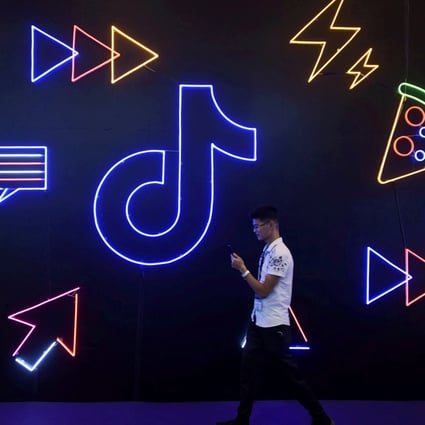 A man holding a phone walks past a sign with the logo of Douyin and TikTok at the International Artificial Products Expo in Hangzhou, Zhejiang province, on October 18, 2019. ByteDance, the owner of the platforms, has been testing paid short dramas on Douyin as it searches for new sources of revenue. Photo: Reuters