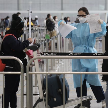 A staff member checks arriving passengers’ health documents at Hong Kong International Airport. Photo: Xiaomei Chen