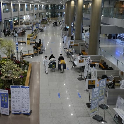 A quarantine officer guides travellers at the arrival hall of the Incheon airport in South Korea on Wednesday. Photo: AP