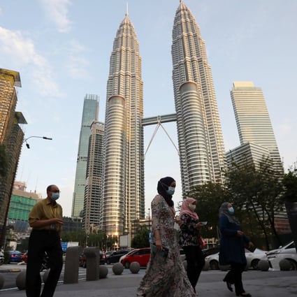 People cross a street in front of the Petronas Twin Towers in Kuala Lumpur. Photo: Reuters