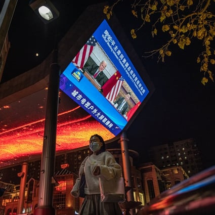 People walk past a big screen showing US President Joe Biden and Chinese President Xi Jinping attending their virtual summit, during the evening news program, in Beijing on November 16. Photo: EPA-EFE