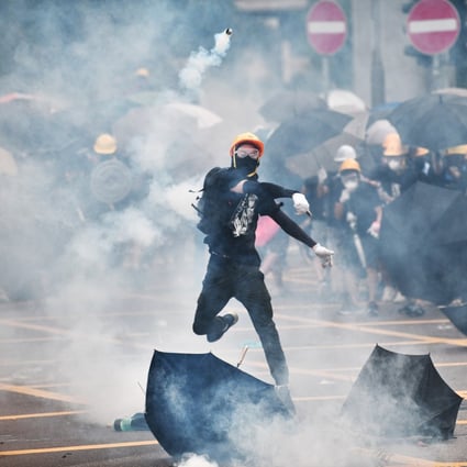 ​​A protester throws tear gas back at police officers during a demonstration in Yuen Long in Hong Kong on July 27, 2019. Photo: AFP