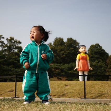 A girl wearing a costume inspired by the Netflix series Squid Game poses in front of a giant doll named Younghee from the series on display at a park in Seoul on October 26. The series, which captures the country’s gaping inequalities and rising household indebtedness, has become an international sensation. Photo: Reuters