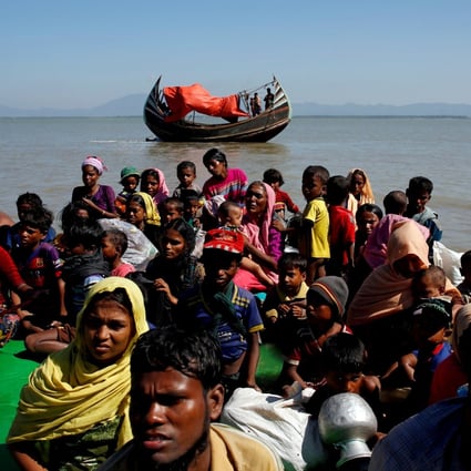 Rohingya refugees sit on a makeshift boat as they are interrogated after crossing into Bangladesh. Photo: Reuters