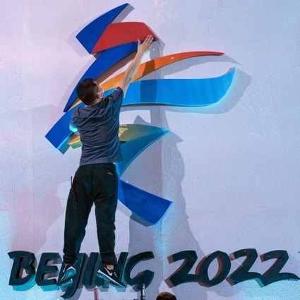An employee fixes the logo for the 2022 Winter Olympics before an event in Beijing in September. Photo: AP