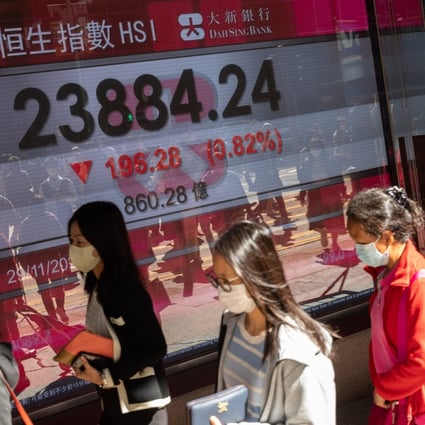 People walk past an electronic board displaying the Hang Seng Index in Hong Kong on November 29. 2021 has been a good year for global stocks, but as many investors in Asia know, not every region’s equity market had such a good year. Photo: EPA-EFE