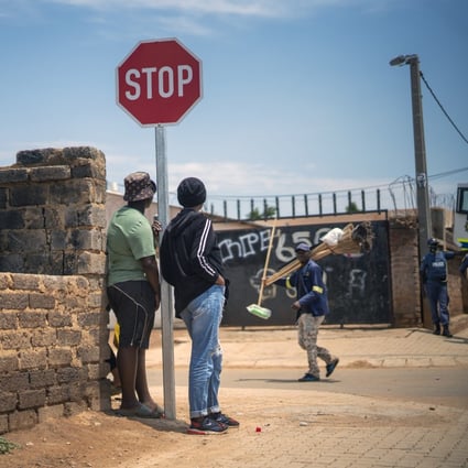 Residents stand in the streets of Lawley, South Africa, during a visit by local government officials for the launch of the Vooma vaccination program against Covid-19. Photo: AP