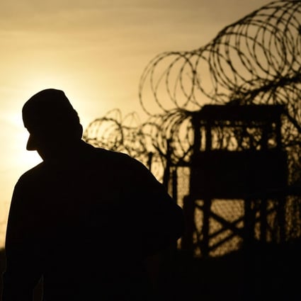 A US soldier walks next to the razor wire-topped fence at Guantanamo Bay, Cuba. Photo: AFP