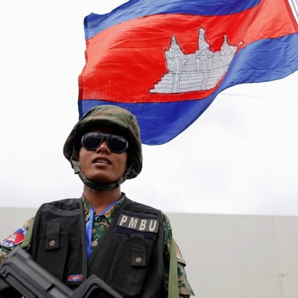 An armed security guard stands under a Cambodian flag in the capital Phnom Penh in November 2012. Photo: Reuters