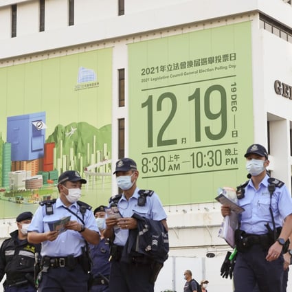 Police in front of a huge banner in Central promoting the Legco poll. Photo: May Tse