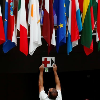 An EU Council employee places a sign near European Union national flags ahead of the EU leaders summit amid the coronavirus pandemic in Brussels, on July 16, 2020. Photo: Reuters 