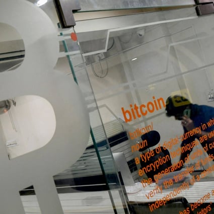 A worker talks on his phone behind a glass partition displaying a bitcoin symbol in an office in Bangalore on November 23. Photo: AFP