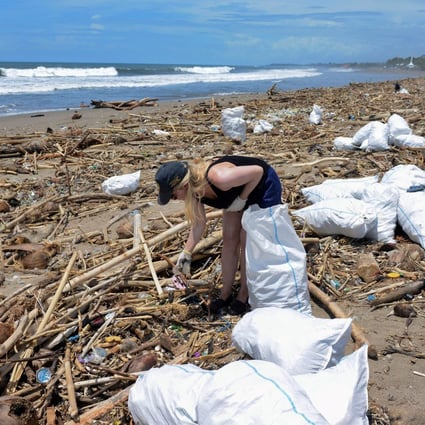 A foreign tourist collects rubbish among piles of debris on Batu Belig beach in Bali after it washed up following an offshore storm. Photo: AFP