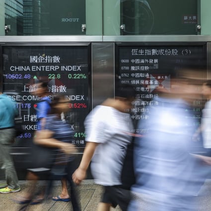 People walking past electronic boards showing recent stock market information in Mong Kok, Hong Kong. Photo: Sam Tsang