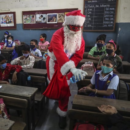 A man dressed as Santa Claus offers hand sanitiser to pupils at a school in Mumbai, India, on Wednesday. Photo: AP