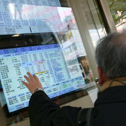 People pointing at an electronic board showing local stock prices in Mong Kok, Hong Kong. Photo: David Wong