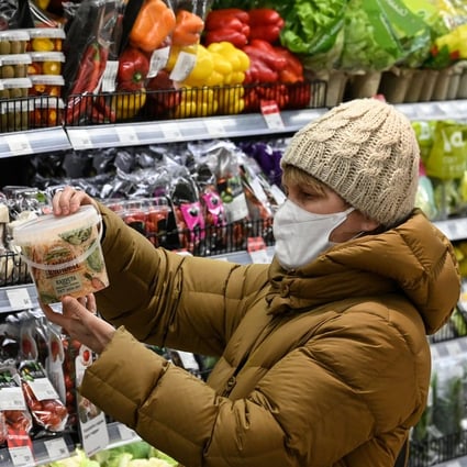 A woman checks pickled food at a supermarket in Moscow on December 15. Price rises are already rippling through economies. Photo: AFP