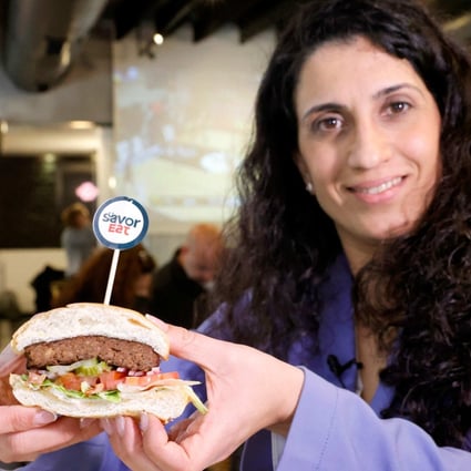 Racheli Vizman, CEO of SavorEat, holds a cut half of a plant-based hamburger made and cooked by a robot in the Israeli coastal town of Herzliya on Monday. Photo: AFP