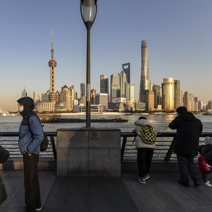 Pedestrians walk along the Bund in Shanghai on December 28 with the city’s financial district in the background. Photo: Bloomberg