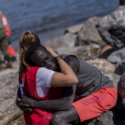 A migrant is comforted by a member of the Spanish Red Cross at the Spanish enclave of Ceuta near the border of Morocco and Spain, in May 2021. Photo: AP