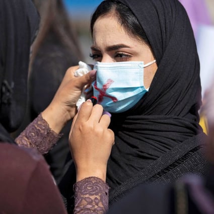 A demonstrator draws a cross on the mask of another protester as they attend a rally for International Women’s Day in Basra, Iraq, on March 8, 2021. Photo: AFP
