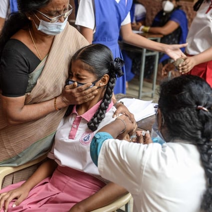 A teacher holds a student as she gets vaccinated against Covid-19 in Hyderabad, India. Photo: AFP