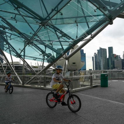 Children ride bikes along the Helix Bridge with a view of the financial business district in Singapore. Photo: AFP
