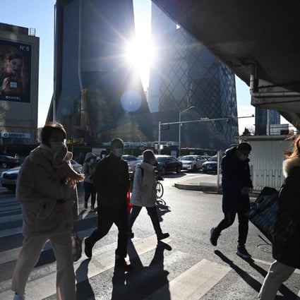 People cross a road in the central business district in Beijing on December 16, 2021. Photo: AFP