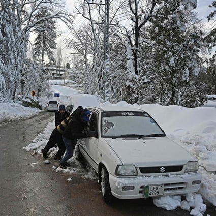 People push a car stuck on a road after a blizzard near the resort town of Murree near Islamabad, Pakistan on January 9. Photo: AFP