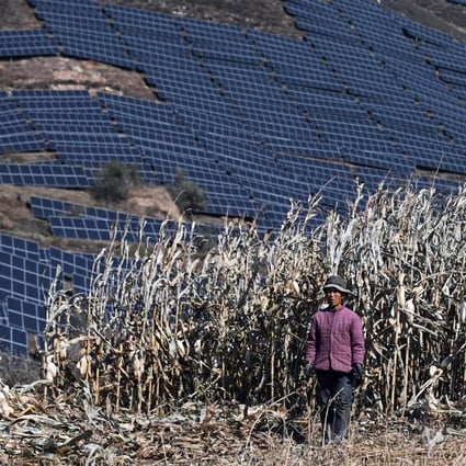 This photo taken on October 23, 2021 shows a farmer in a field near solar panels on a hillside at Huangjiao village in Baoding, China’s northern Hebei province.  Photo: AFP