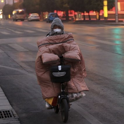 A woman wearing a face mask rides down a mostly empty street in Xi’an, China on January 6. Photo: Chinatopix via AP